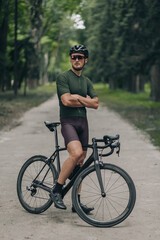 Fototapeta premium Cyclist in activewear standing with his bike at green park