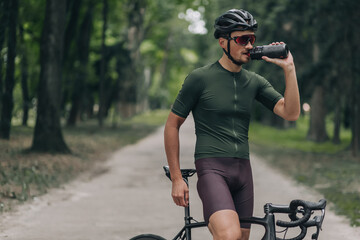 Tired cyclist drinking water after intensive ride outdoors.