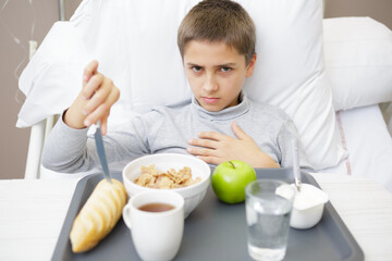 small boy with catheter having lunch in hospital