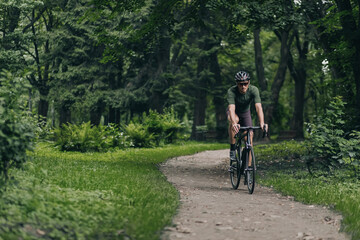 Fototapeta na wymiar Muscular man cycling along city park during morning time