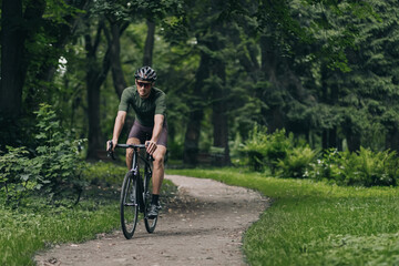 Fototapeta na wymiar Healthy and active cyclist riding bike among city park