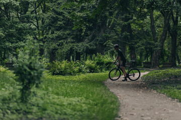 Male cyclist in sport clothes riding bike on park trail