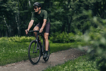Fototapeta premium Positive sporty man having active cycling outdoors