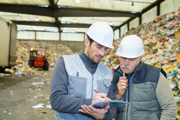 male co-workers looking at clipboard in recycling center