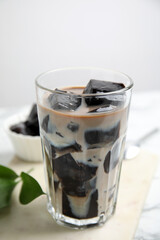 Glass of milk with grass jelly on table, closeup