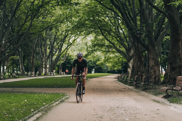 Fototapeta premium Man in helmet and glasses riding black bike outdoors