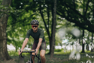 Fototapeta na wymiar Man in helmet and glasses using bike for training outdoors