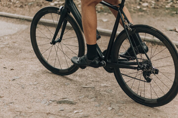 Close up of man with muscular legs riding black bike