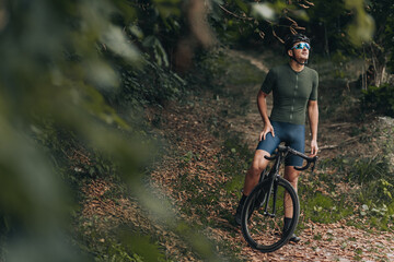 Obraz premium Sportsman in helmet and glasses resting on bike outdoors