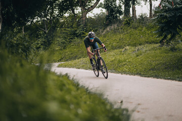 Fototapeta premium Active caucasian man in sportswear riding bike at park