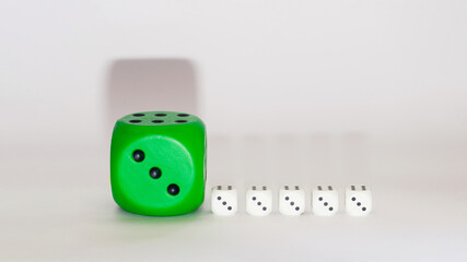 green dice next to white little white dices on a white background with shadows.still life visual design