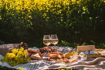 picnic on sunset at rapeseed field glass of wine food bun