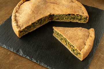 Swiss chard pie on black slate. Homemade baked food from leaves.