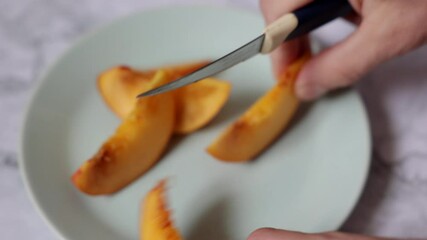 Process and slicing a peach and dividing it into wedges against the background of a plate. Juicy and ripe fresh fruits. Preparing fruits for serving.
