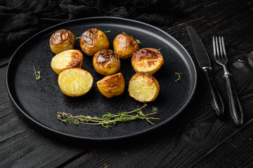 Roasted Potatoes with Rosemary, on plate, on black wooden table background
