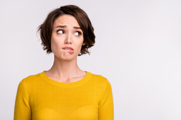 Photo of stressed brunette millennial lady bite lip look empty space wear yellow shirt isolated on...