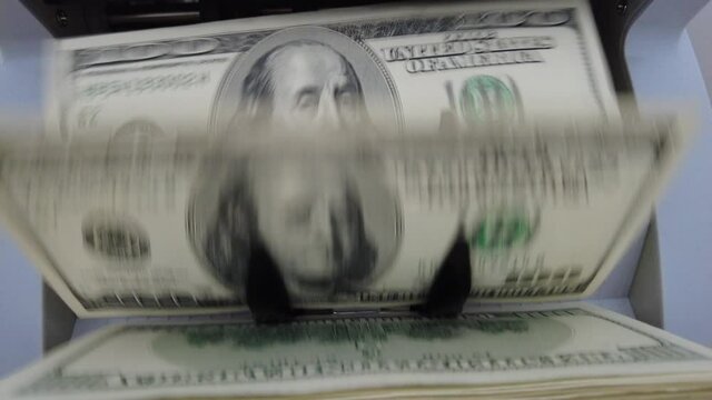 Counting machine for banknotes. Dollars in a calculating machine. Recalculation of dollar bills. American dollars are counted by a machine for banknotes.