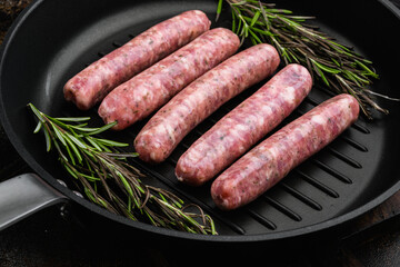 Raw Sausages with Herbs and Spices, on frying cast iron pan, on old dark rustic table background