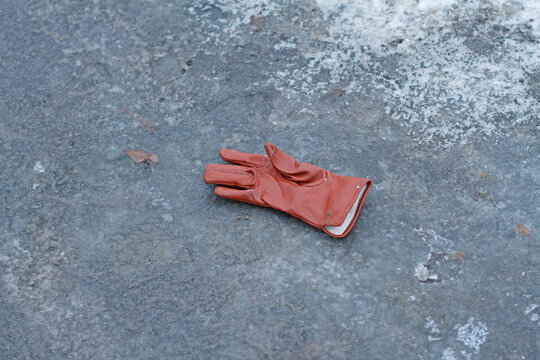 Forgotten brown leather glove lies on the icy asphalt