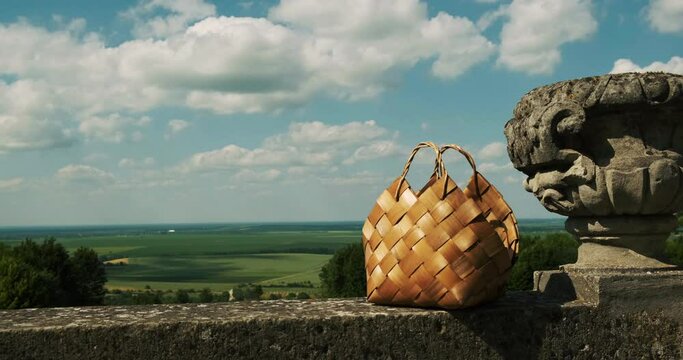 Wooden basket for a picnic standing on the antique balcony with statue. Autumn garden the landscape view panorama side view on blue sky and green landscapes, no people, calm view. Product packshot