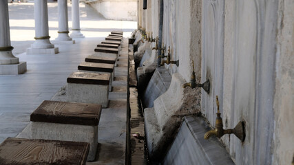 Ablution or wudhu station at mosque in Istanbul, Turkey. Faucets for ritual ablution and stones to sit on near a mosque in Islamic culture. Turkish Ottoman style water tap.