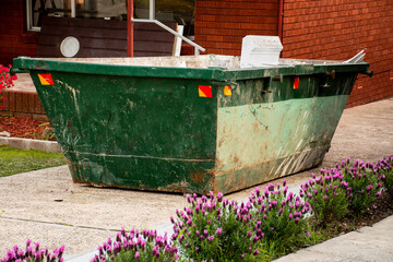 Skip bin with household waste rubbish on a front yard. House clean up concept.