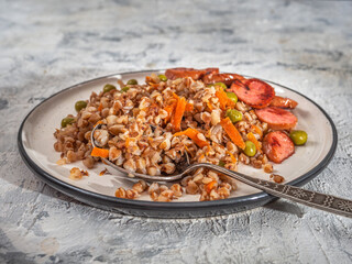 Breakfast plate of buckwheat porridge, fried sausage and vegetables