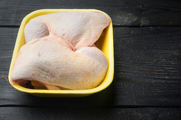 Fresh Chicken Whole Legs, in Foam Tray Pack, on black wooden table background, with copy space for text