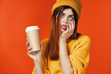 pretty woman in yellow hat with a cup of hot drink in hands emotions isolated background