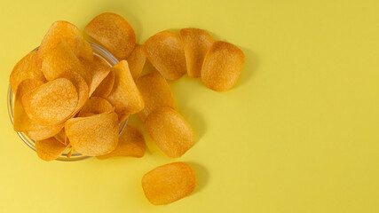 bowl with potato chips on a yellow background. Top view, copy space