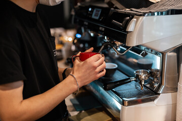Man barista makes delicious coffee near coffee machine indoors. Close-up of male hands brewing coffee
