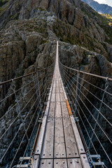 Wooden suspended cable narrow bridge in the Swiss Alps. Trift bridge, Triftbrücke. Summer, day, no people