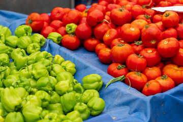 Green bell peppers and tomatoes on vegetable market.