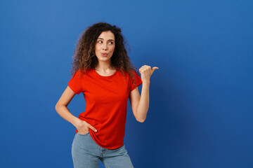 Fototapeta premium Young brunette woman with wavy hair looking and pointing finger aside