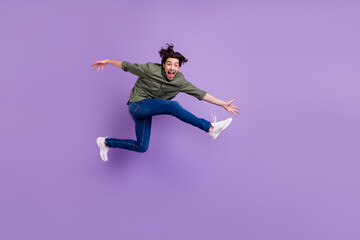 Full size photo of crazy positive happy young man jumper up run empty space cool isolated on purple color background