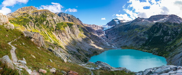 Naklejka na ściany i meble Trift glacial mountain lake in the Bernese Swiss Alps.panoramic view, stacked panorama. Summer, daytime,clouds, blue sky, no people