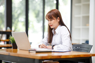 Asian young women or businesswomen working, doing Financial analysis the graph of the company's performance to create profits and growth, Market research reports income statistics accounting.