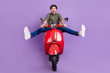 Full length photo of positive cheerful crazy young man ride bike enjoy speed isolated on purple color background