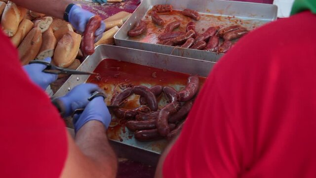 Preparando para degustar bandeja de chorizos cocidos en vino para hacer bocadillos con pan en fiesta tradicional 