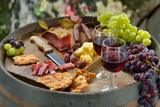 Beim Törggelen in Südtirol mit den klassischen Spezialitäten auf einem Weinfaß dazu regionaler Rotwein