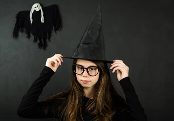 Halloween. Teenage girl dressed as a witch celebrating Halloween. Copy space. Black background.