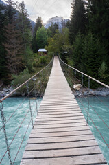 Obraz premium Suspension bridge over the mountain river Teberda. Forest, nature reserve.