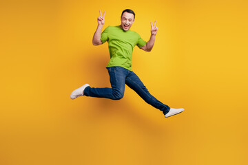 Fototapeta na wymiar Portrait of funky excited energetic guy jump show v-sign on yellow wall