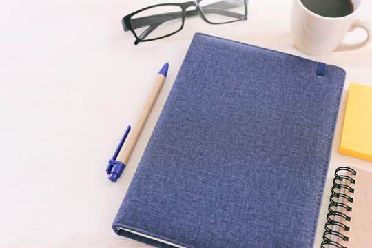 top view image of open notebook with blank pages next to cup of coffee on wooden table. ready for adding text or mockup