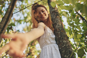 joyful red-haired woman in the forest near the tree nature summer