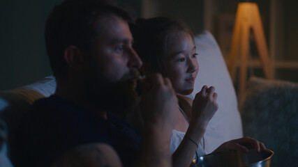 Father and daughter watching movie in evening