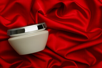 Jar of hair care cosmetic product on red fabric, top view. Space for text