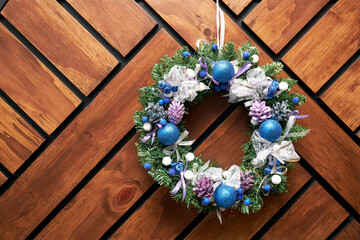 christmas wreath in blue shades hanging on a wall of wooden boards