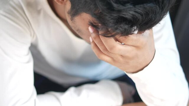 Close up of sad man covering face with hand.