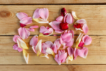 Colorful rose petals on a wooden background. Top view. Flat lay. Holiday background, template for a postcard